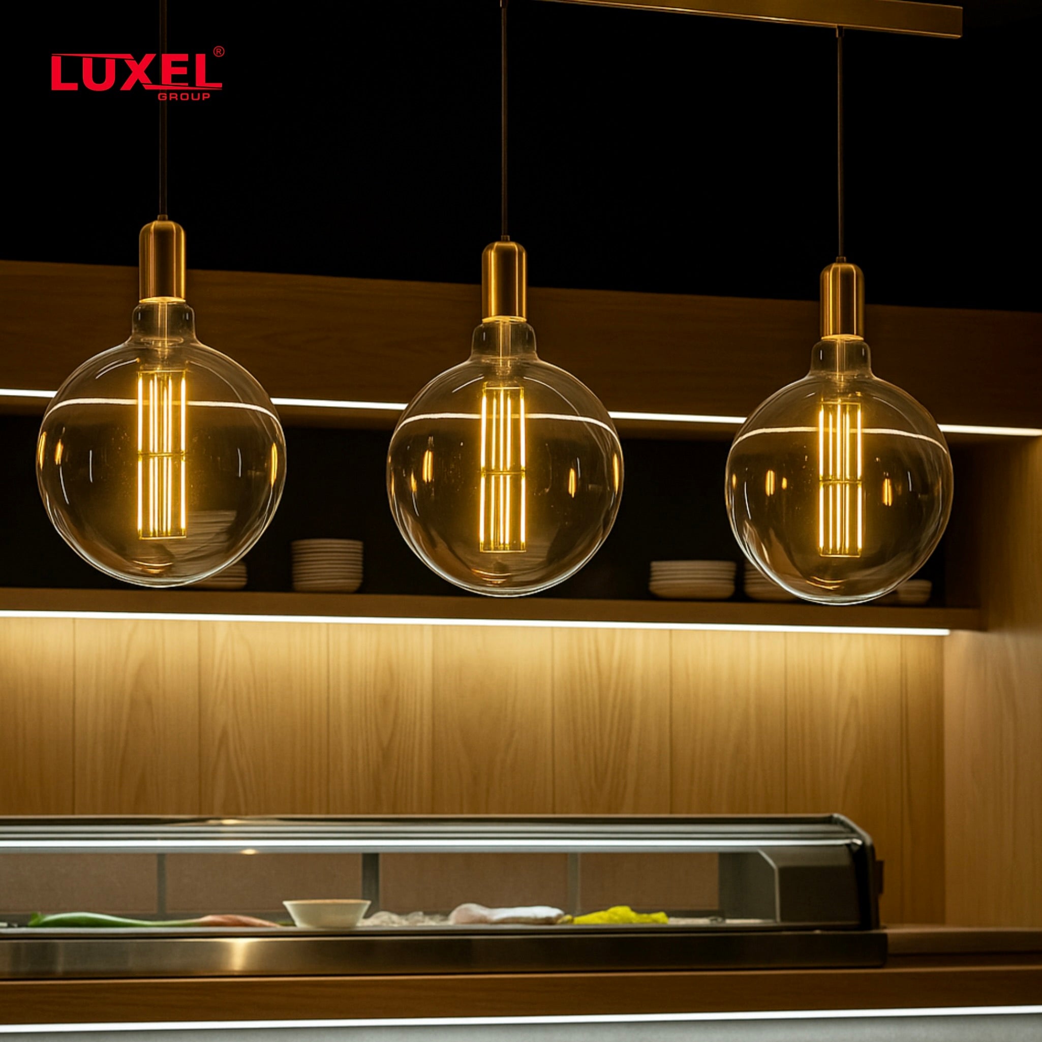 Three Luxel pendant lights hanging above a kitchen counter with a modern interior design.