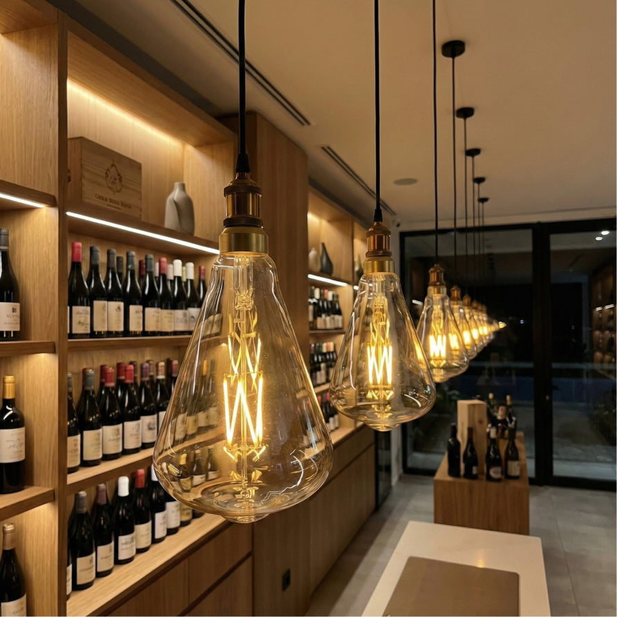 Vintage-style pendant lights hanging in a wine cellar with wine bottles on shelves.