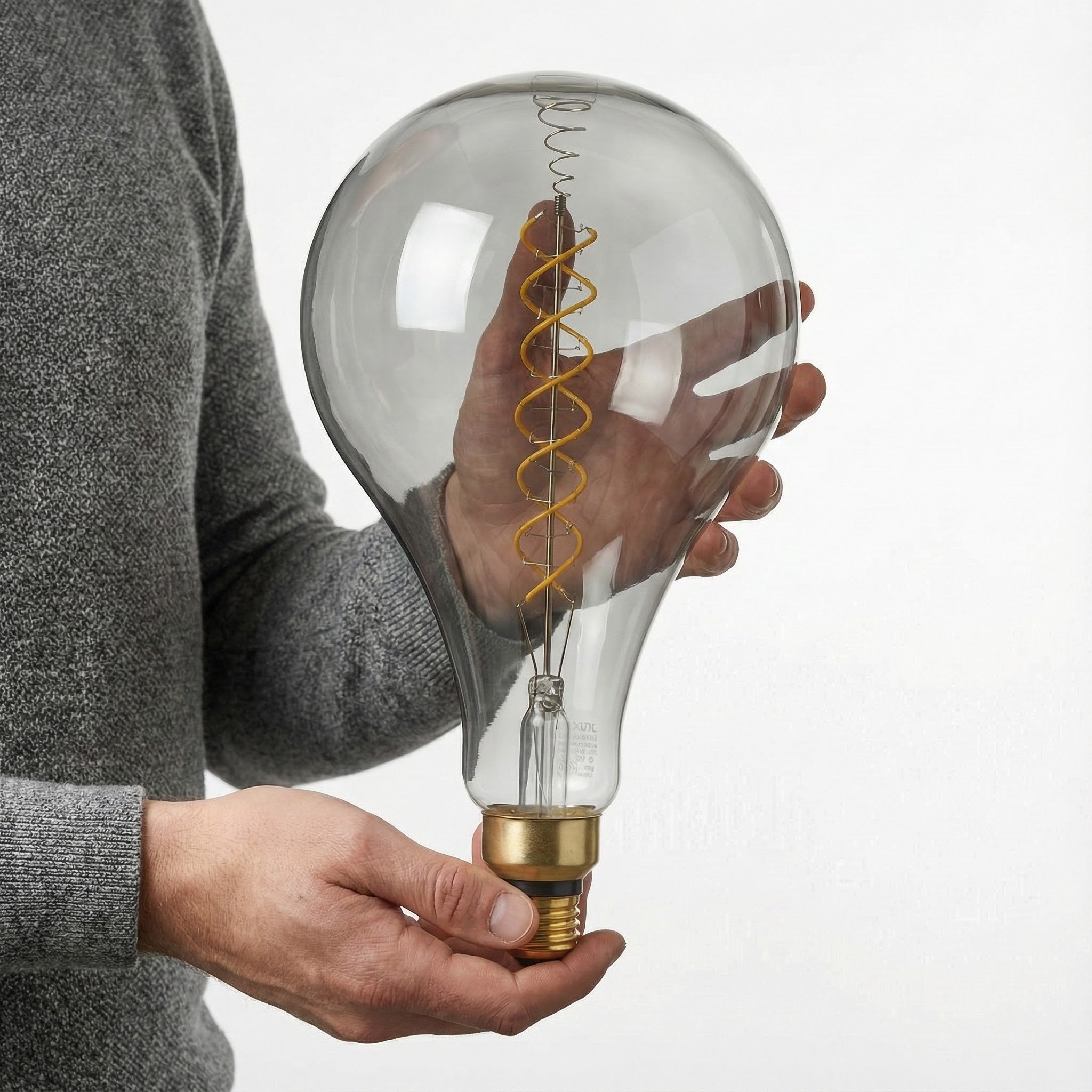 Person holding a large, decorative light bulb with a coiled filament inside.