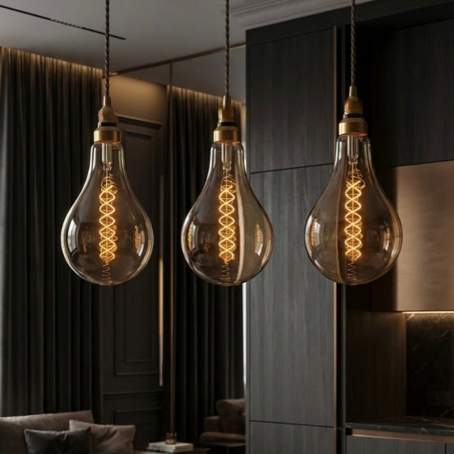 Three vintage-style light bulbs hanging in a room with dark walls and furniture.