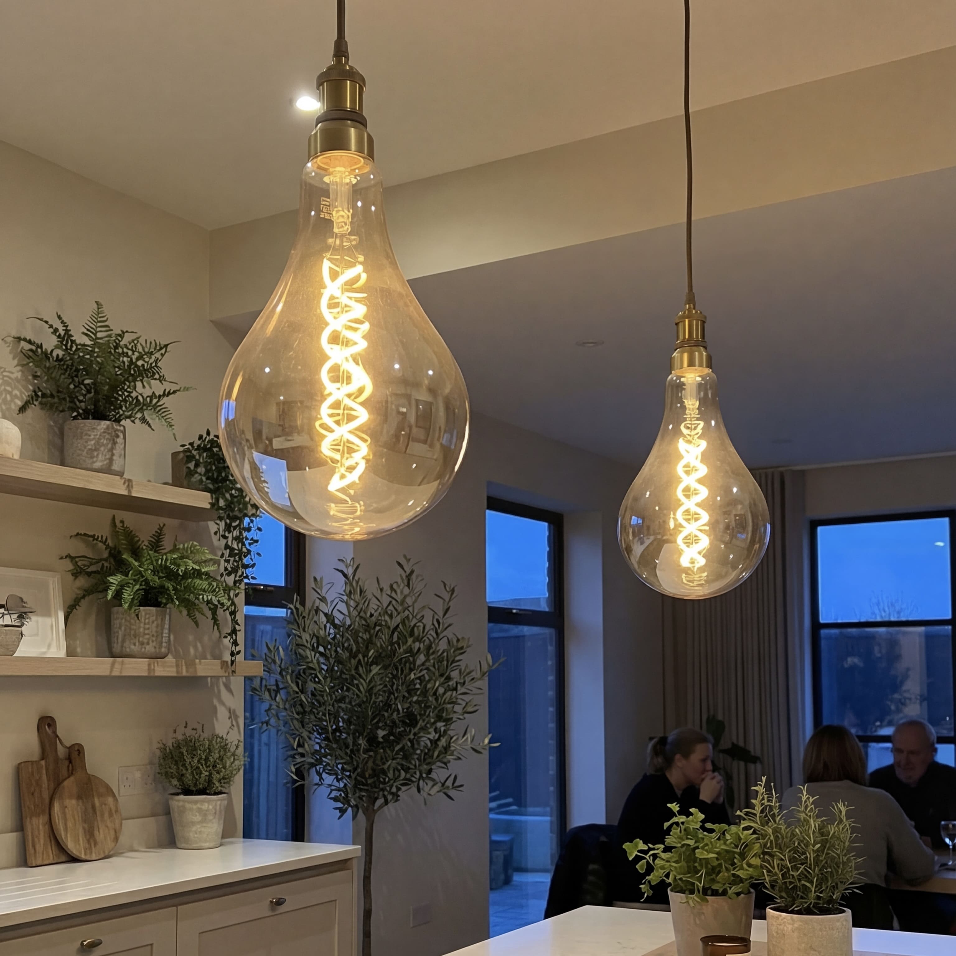 Two large illuminated light bulbs hanging from the ceiling in a modern kitchen.