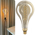 Vintage-style light bulb with decorative spiral filament next to a plain background