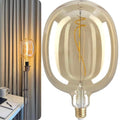 Large decorative light bulb with a visible filament next to a smaller traditional light bulb on a neutral background.