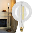 Vintage-style light bulb with a decorative lamp in a room setting.