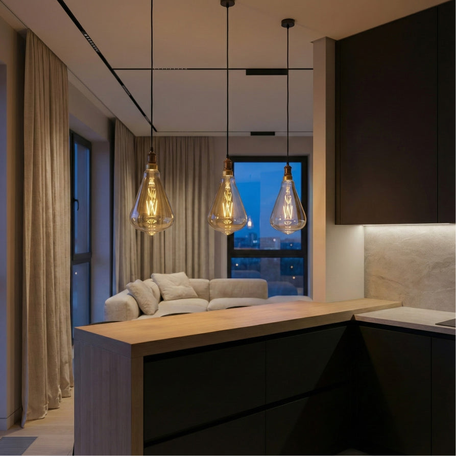 Modern kitchen and living room with pendant lights and a view of the city at night.