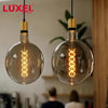 Luxel light bulbs hanging in a modern office setting with a man using a tablet.
